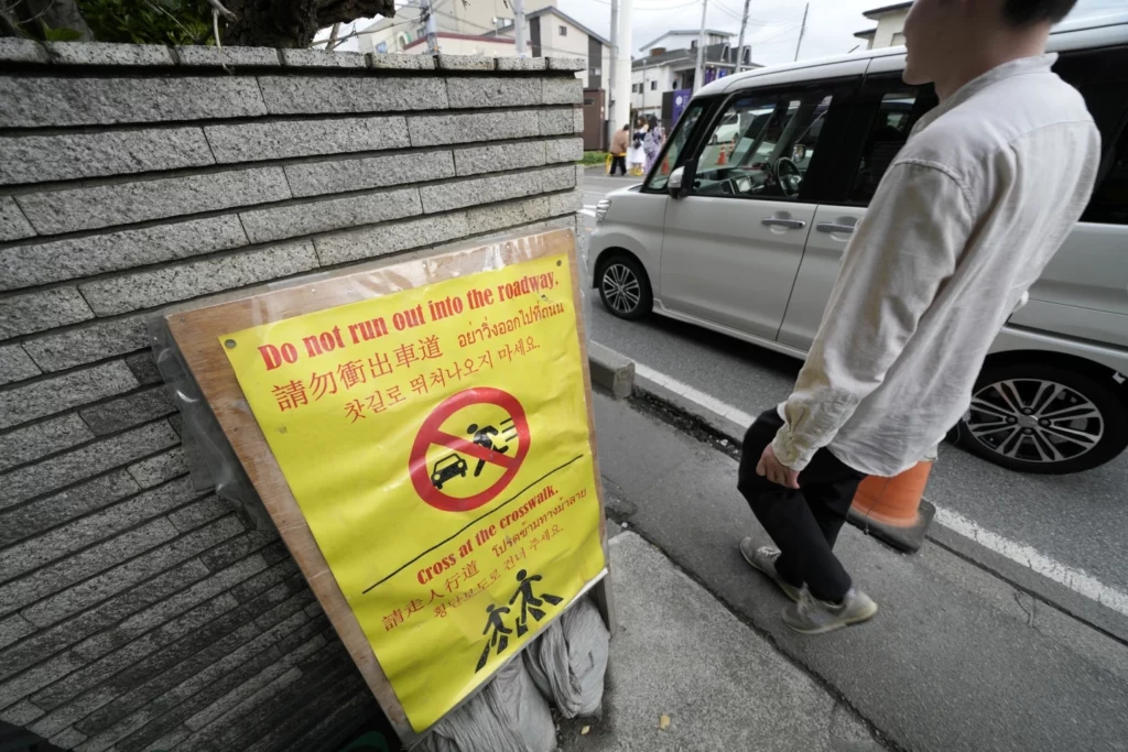 Photo 2 : A notice for tourists across the use road from the Lawson convenience store, where a popular photo spot framing a picturesque view of Mount Fuji in the background. 